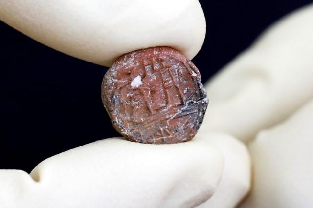 A conservator shows a 2,700-year-old clay seal impression which archaeologists from the Israel Antiquities Authority say belonged to a biblical governor of Jerusalem and was unearthed in excavations in the Western Wall plaza in Jerusalem’s Old City