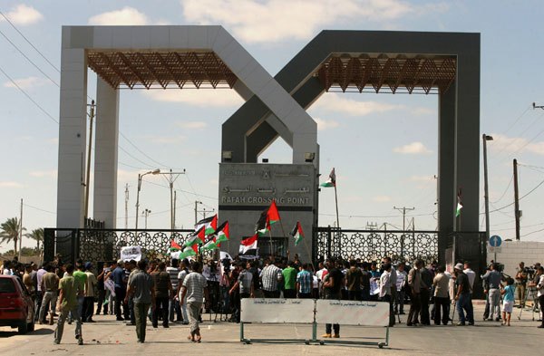 Palestinians wave a national flag and an Egyptian flag as they take part in a rally calling on Egyptian authorities to open the Rafah crossing, outside the crossing