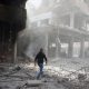 A man walks on rubble at a damaged site after an airstrike in the besieged town of Douma