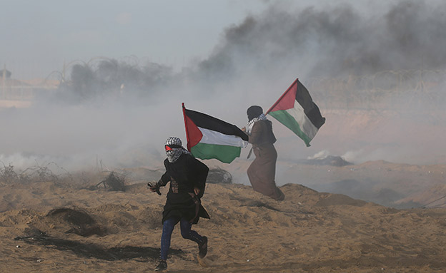Palestinian women run during a protest at the Israel-Gaza border fence in the southern Gaza Strip