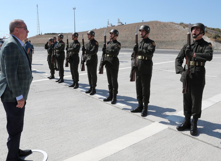 Turkish President Erdogan reviews a guard of honour at the airport in Bursa