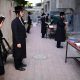orthodox jewish men pray outside a closed yeshiva
