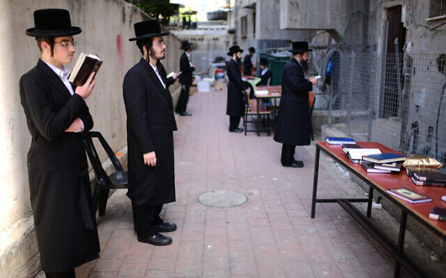 orthodox jewish men pray outside a closed yeshiva
