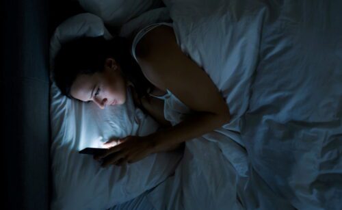 Woman In Bed With Mobile Phone