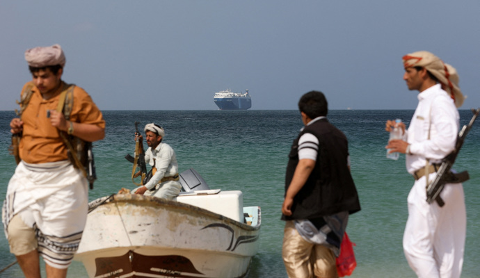 FILE PHOTO: Armed men stand on the beach as the Galaxy Leader commercial ship, seized by Yemen’s Houthis last month, is anchored off the coast of al-Salif