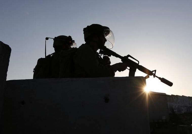 Israeli soldiers keep guard during a protest by Palestinians against the Israeli offensive in Gaza, at Qalandia checkpoint near the West Bank city of Ramallah